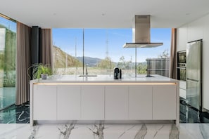 A modern kitchen with a marble countertop, stainless steel appliances, and a view of the outdoors.