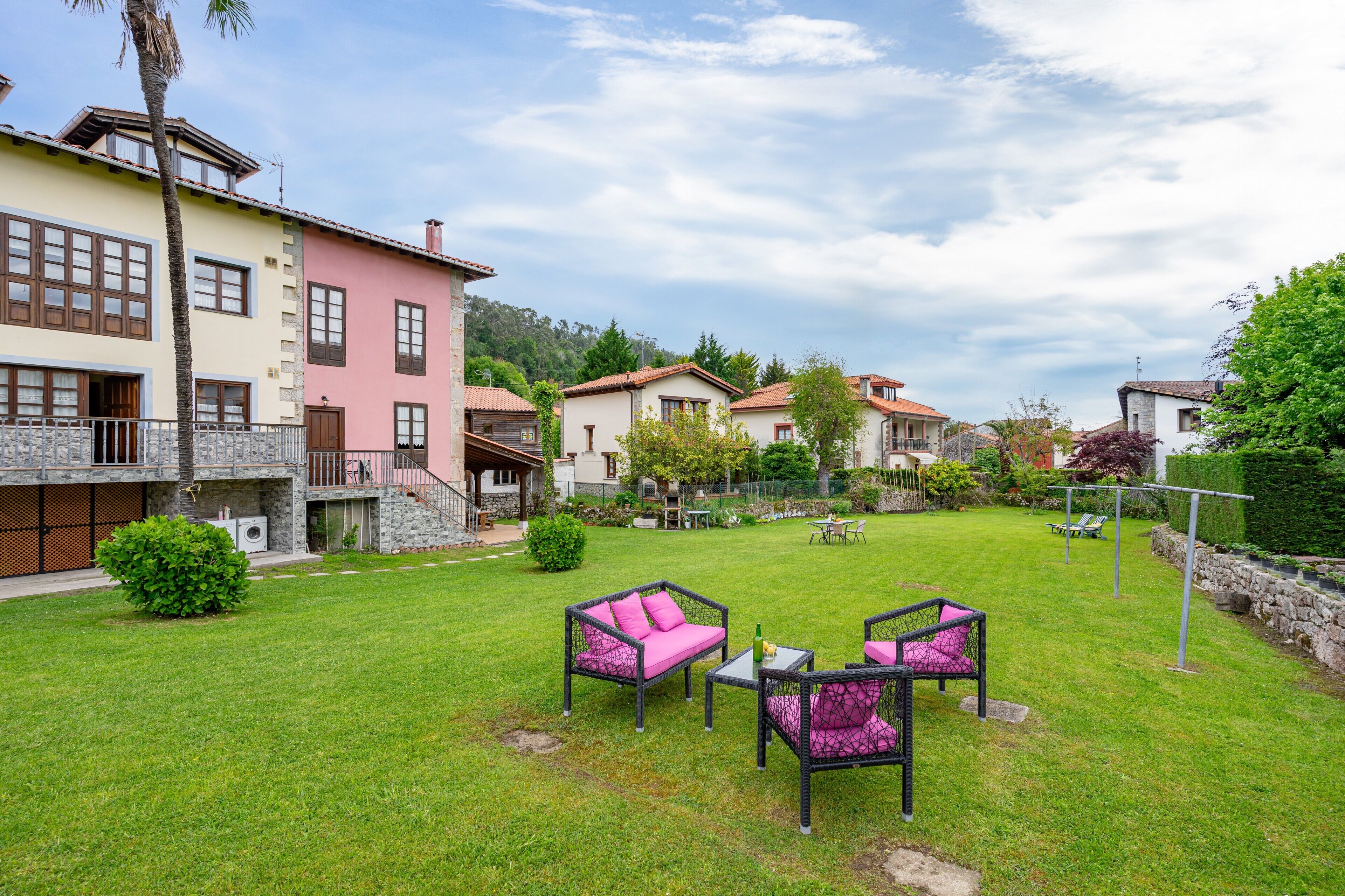 Un barrio residencial con un césped cuidado, mobiliario exterior y casas con balcones.