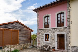Un edificio de piedra con fachada rosa, una puerta de madera y un banco en el exterior.