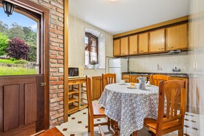 Una cocina con armarios de madera, una mesa de comedor con sillas y vista al exterior.