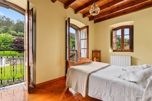 Un dormitorio con cama, ventana y vista a zonas verdes.