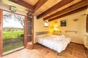 A bedroom with a bed, a door leading to a balcony, a wall-mounted light, and a painting.