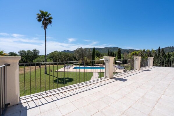 A rooftop terrace with a pool, a lawn, and a view of the mountains.
