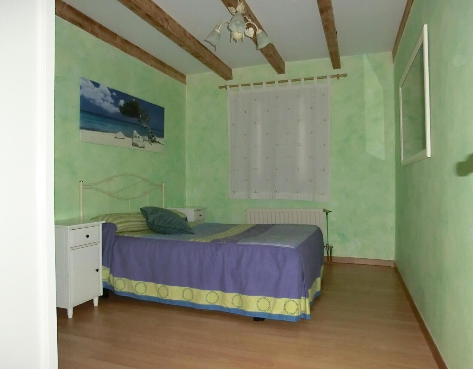 Ein Schlafzimmer mit einem Bett, einem Nachttisch und einem Bild an der Wand.