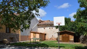 Una cancha de baloncesto con un aro, una mesita y un edificio con tejado de baldosas.