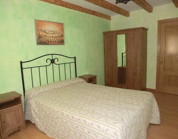 Un dormitorio con una cama, un armario de madera y un cuadro en la pared.