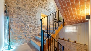 Un escalier avec des murs en pierre, un plancher en bois et une rampe en métal.