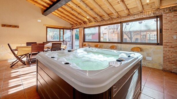 A spa area with a hot tub, wooden ceiling beams, and large windows.