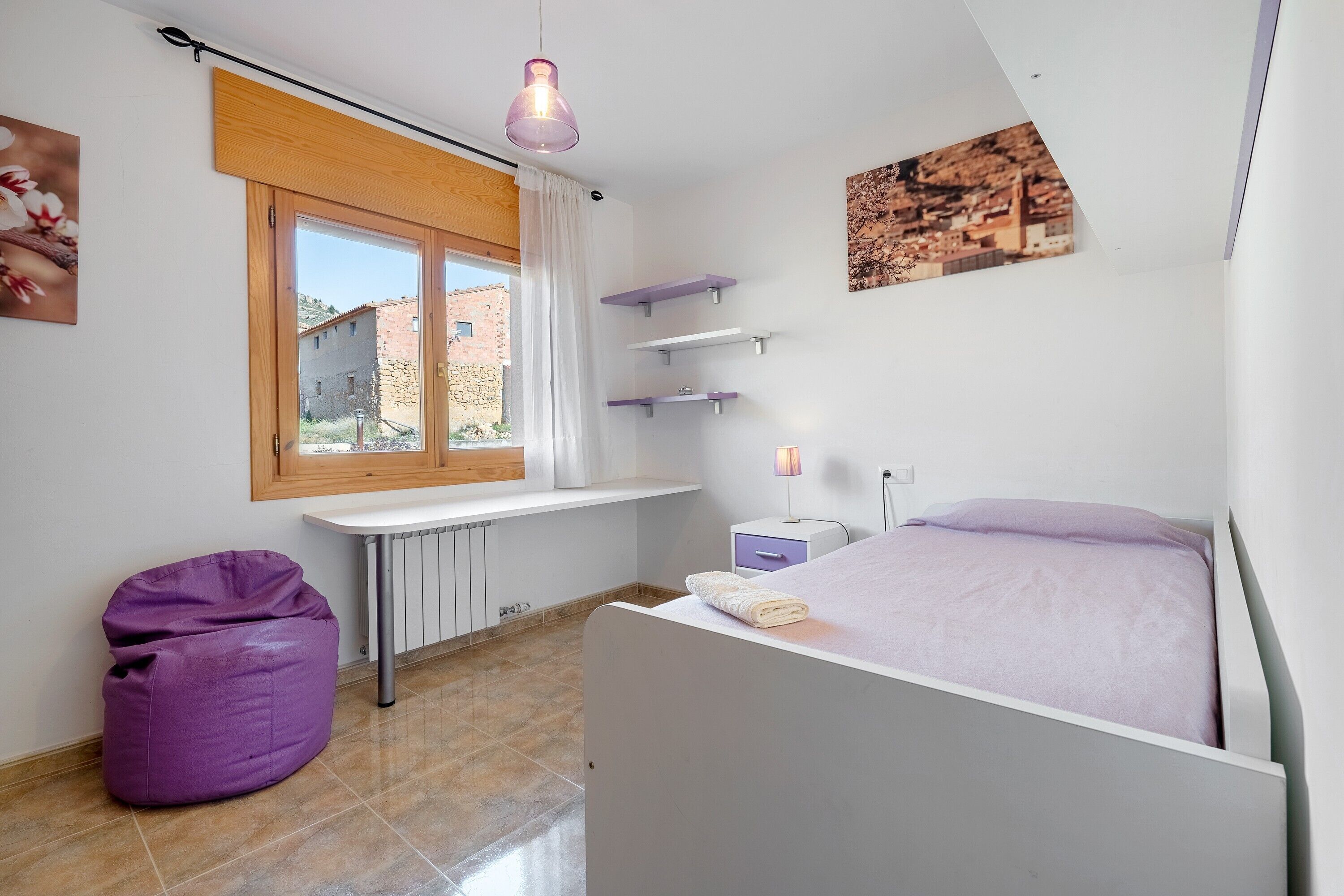 Ein Schlafzimmer mit Bett, Fenster, Schreibtisch und Sitzsack.