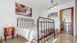 A bedroom with a bed, bedside table, lamp, and artwork on the wall.