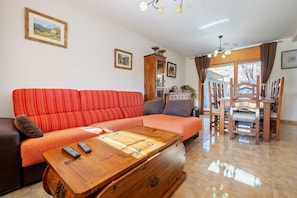 A living room with a sofa, wooden coffee table, and a dining area with chairs and a table.