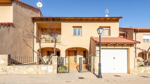 A two-story building with a stone facade, a tiled roof, and a gated entrance.