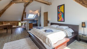 Un dormitorio con techo inclinado, una cama, un escritorio y un tragaluz.