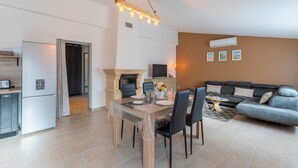 A modern living room with a dining table, sofa, and kitchen area.