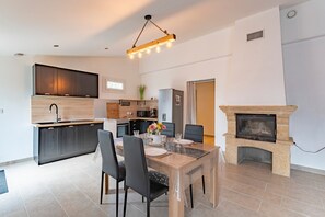 A modern kitchen with dark cabinets, a central island, and a dining area with a table and chairs.