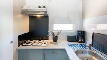 Une cuisine compacte équipée d’une cuisinière à gaz, d’une machine à café et d’un évier.