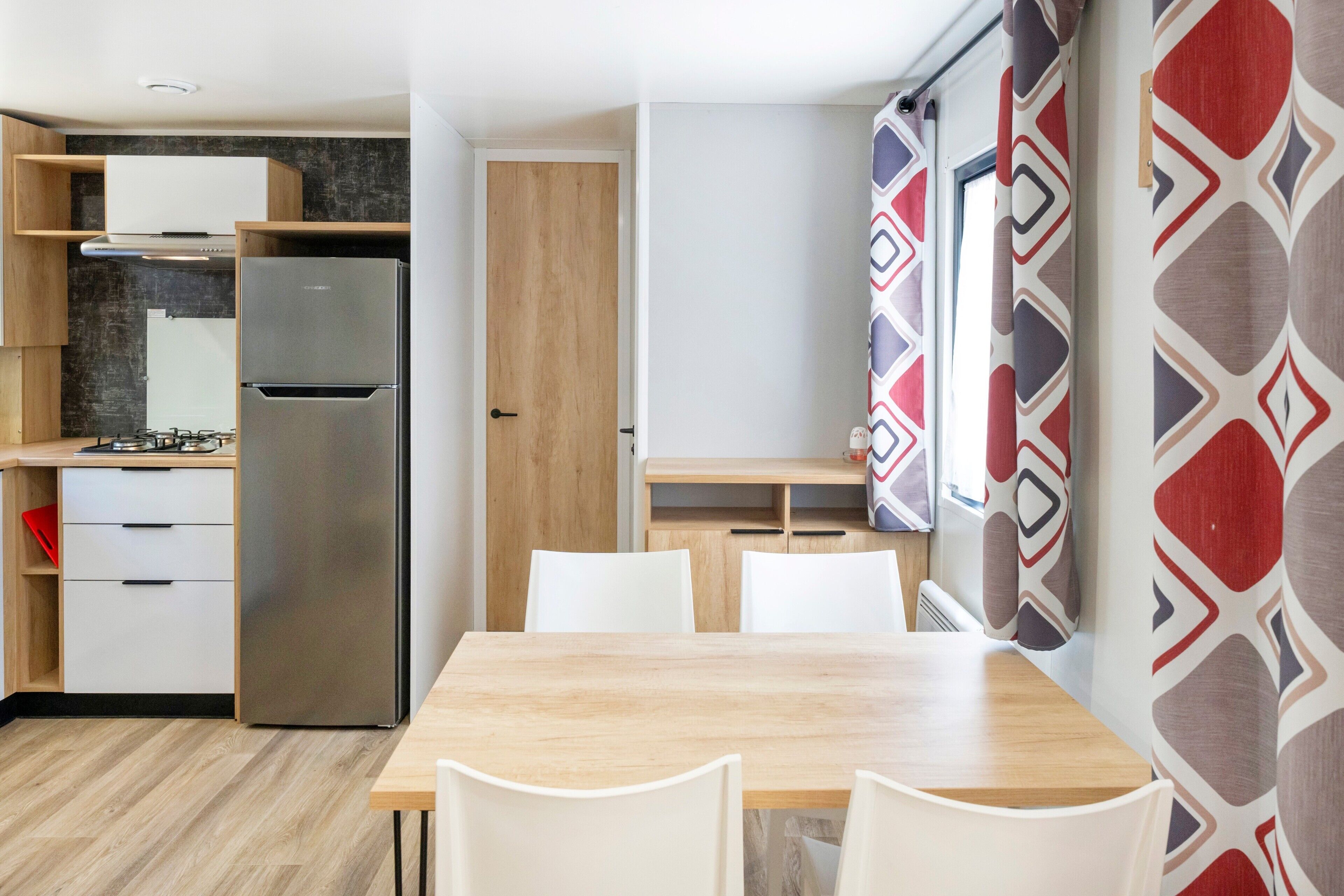 Une cuisine compacte équipée d’un réfrigérateur encastré, d’une cuisinière et d’un meuble en bois.