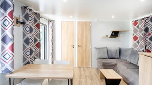 Ein modernes Interieur mit einem Holzesstisch, weißen Stühlen, einem grauen Sofa und einer kleinen Bank.