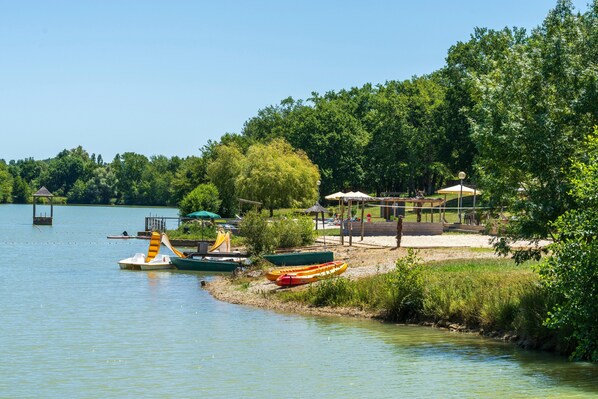 Una zona junto al lago con barcos, un pabellón y una playa de arena.