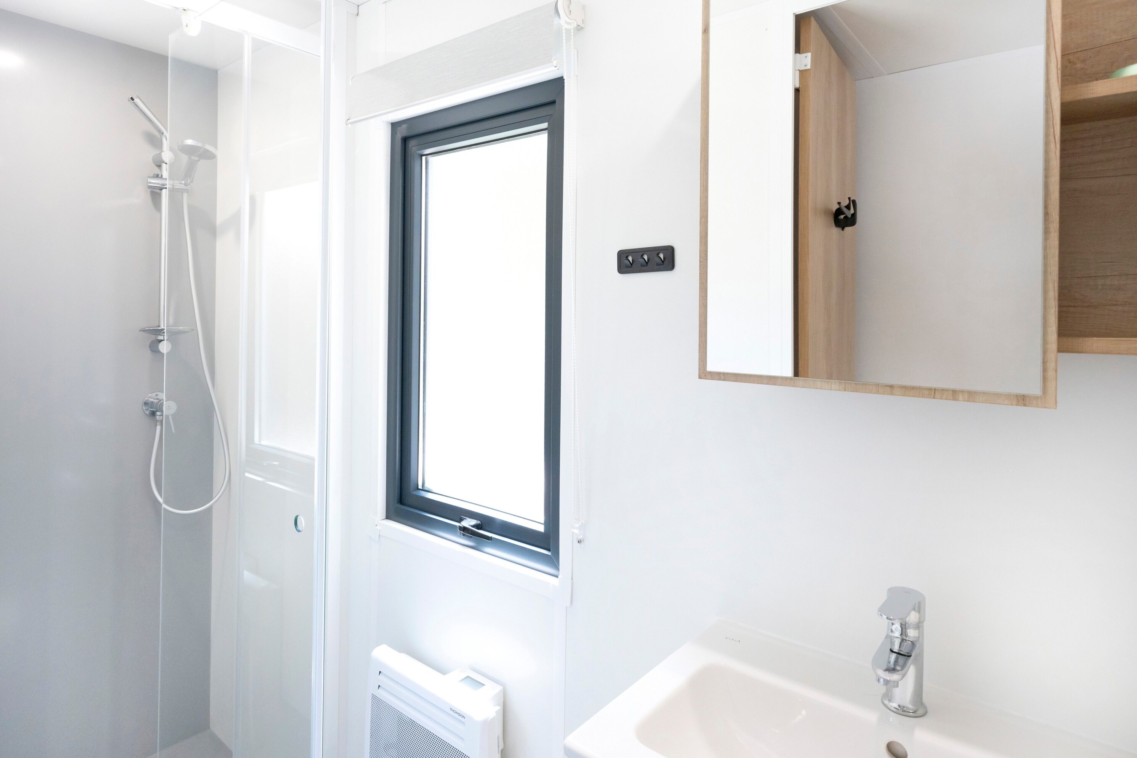 A modern bathroom with a shower, a sink, and a mirror.
