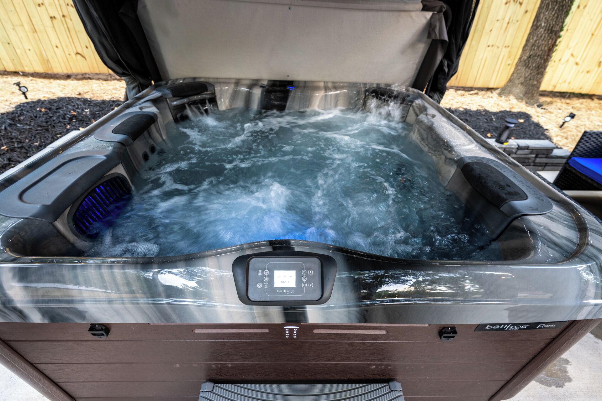 Un jacuzzi con panel de control, rodeado por una terraza de madera.