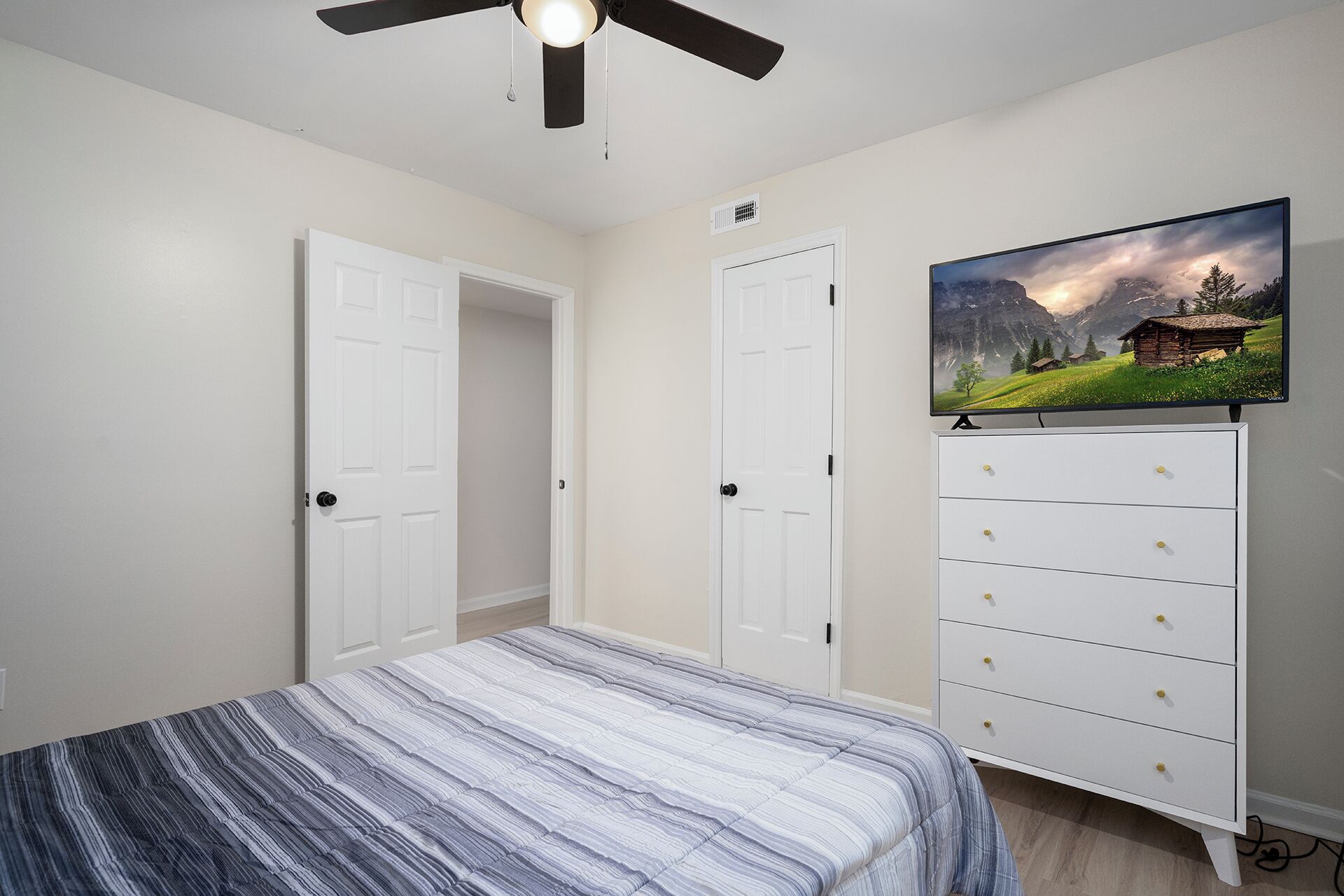 Een slaapkamer met een bed, een dressoir en een televisie aan de muur.