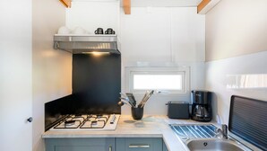 Una cocina compacta con estufa a gas, cafetera y lavamanos.