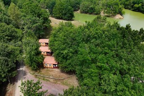 A cluster of rustic cabins surrounded by dense forest, with a dirt path leading to them.