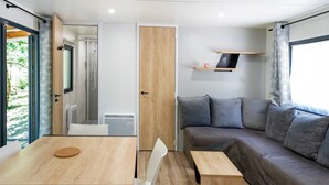 A modern interior with a wooden table, a grey sofa, and a small shelf with a cup.