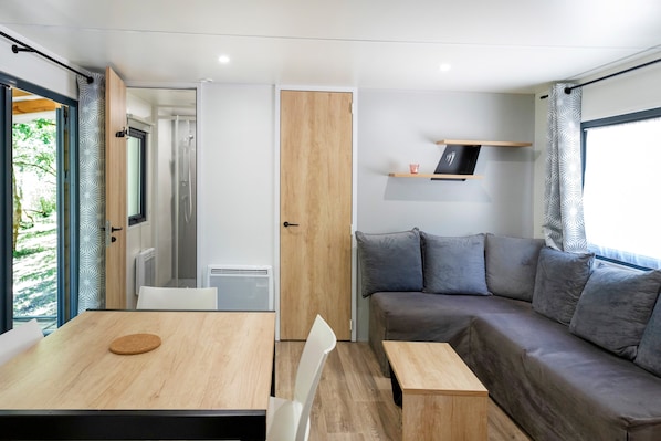 Un interior moderno con una mesa de madera, un sofá gris y una pequeña estantería con una taza.