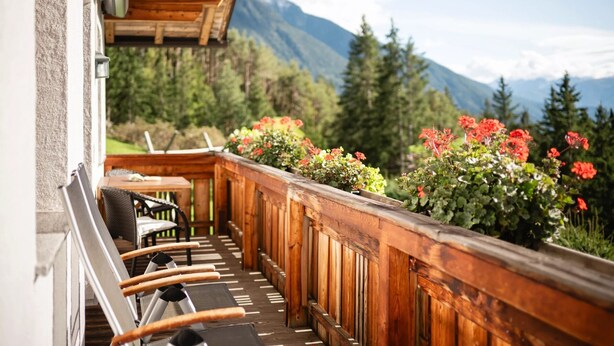 Ein Holzbalkon mit Blick auf Berge, einem Tisch und Stühlen.