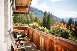 A wooden balcony with a view of mountains, a table, and chairs. - Apartment 'Rieplechn App Bergblick' with Mountain View, Shared Garden and Wi-Fi (Sand in Taufers)