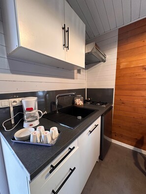 A kitchen with a coffee maker, sink, and white cabinets.