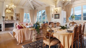 A dining room with a table set for six, a fireplace, and a large window with curtains. - Villa 'La Provenzale' with Mountain Views, Wi-Fi and Air Conditioning (Camaiore)