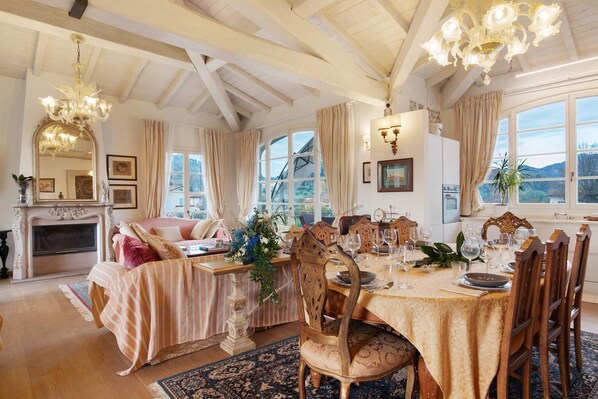 Un comedor con una mesa dispuesta para seis personas, una chimenea y un amplio ventanal con cortinas.