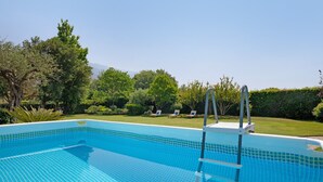 A clear blue swimming pool with a ladder, surrounded by a well-maintained lawn and trees. - Villa 'La Provenzale' with Mountain Views, Wi-Fi and Air Conditioning (Camaiore)
