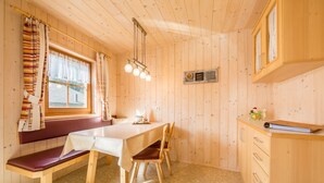 Interior de una cabaña de madera con una mesa de comedor, un banco y armarios.
