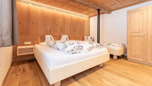 A bedroom with a wooden ceiling, a bed with floral bedding, a nightstand, and a wardrobe.
