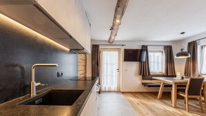 A modern kitchen with a built-in oven, a sink, and a dining area with a table and chairs.