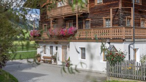 A traditional wooden house with a balcony, a bench, and potted plants.