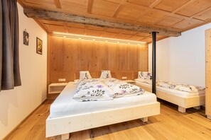 A wooden-paneled bedroom with a large bed, two smaller beds, and a nightstand.