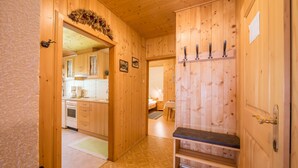 Un interior de madera con cocina, un banco y una puerta con ganchos.