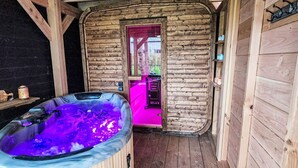 A wooden cabin with a hot tub and a door leading to an outdoor area.