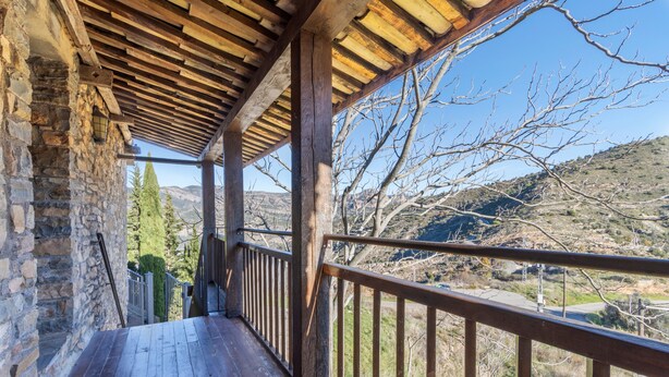 A wooden balcony with a view of a mountainous landscape.