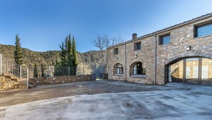 A stone building with arched doorways, a concrete courtyard, and a metal fence.