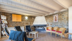 A stone-walled room with a fireplace, wicker furniture, and a sign reading 'PALLARS JUSSA.'
