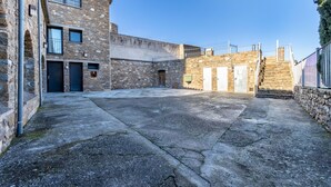 A courtyard with stone buildings, a staircase, and a metal fence.
