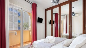 Un dormitorio con una cama, televisión, puerta corrediza de vidrio y espejo.