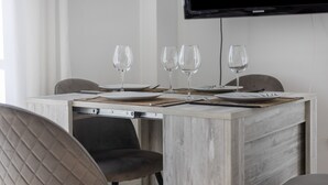 Una mesa de comedor con cuatro copas de vino, platos y cubiertos, dispuesta con un mantel individual.