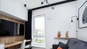 A modern living room with a grey sofa, a wooden desk, and a TV. - Platon 46 Modern Studio (Łódź)